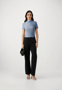 Blue short-sleeve top with a textured pattern, paired with high-waisted black wide-leg jeans and beige strappy heels. Holding a black clutch.