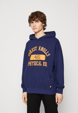 Mörkblå hoodie med en orange grafisk tryck som står "FOREST KNOLLS 415 PHYSICAL ED." samt en kangoru ficka. Mjuk tyg, avslappnad passform.