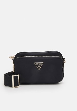 Sac bandoulière noir Guess avec fermeture éclair dorée, sangle réglable et logo métallique triangulaire sur la poche avant.