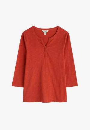 Kõrge kaelusega rust värvi pikeeritud särk, mis on valmistatud pehmest kangast ja sisaldab kolme nupuklappi. Sile tekstuur ja vabalt langev liikumine.