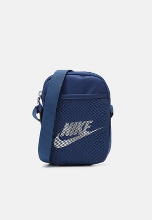 Petit sac banane Nike bleu marine avec une sangle ajustable et un logo blanc sur la poche avant en mesh.