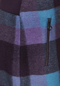 Texturerad tyg med djärva lila och blå rutmönster, med en sidodragkedja. Lämplig för stiliga, avslappnade kläder.