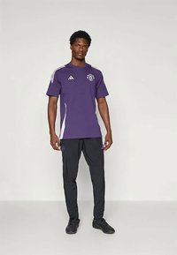 Purple athletic shirt with white side panels and logo, paired with black pants featuring purple accents, both made of smooth, lightweight fabric.