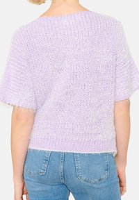 Vaaleanliila kevyt neulotumpi, jossa on lyhyet hihat, löysä istuvuus ja pehmeä rakenne. Ripsureunat tuovat lisäyksityiskohtia.