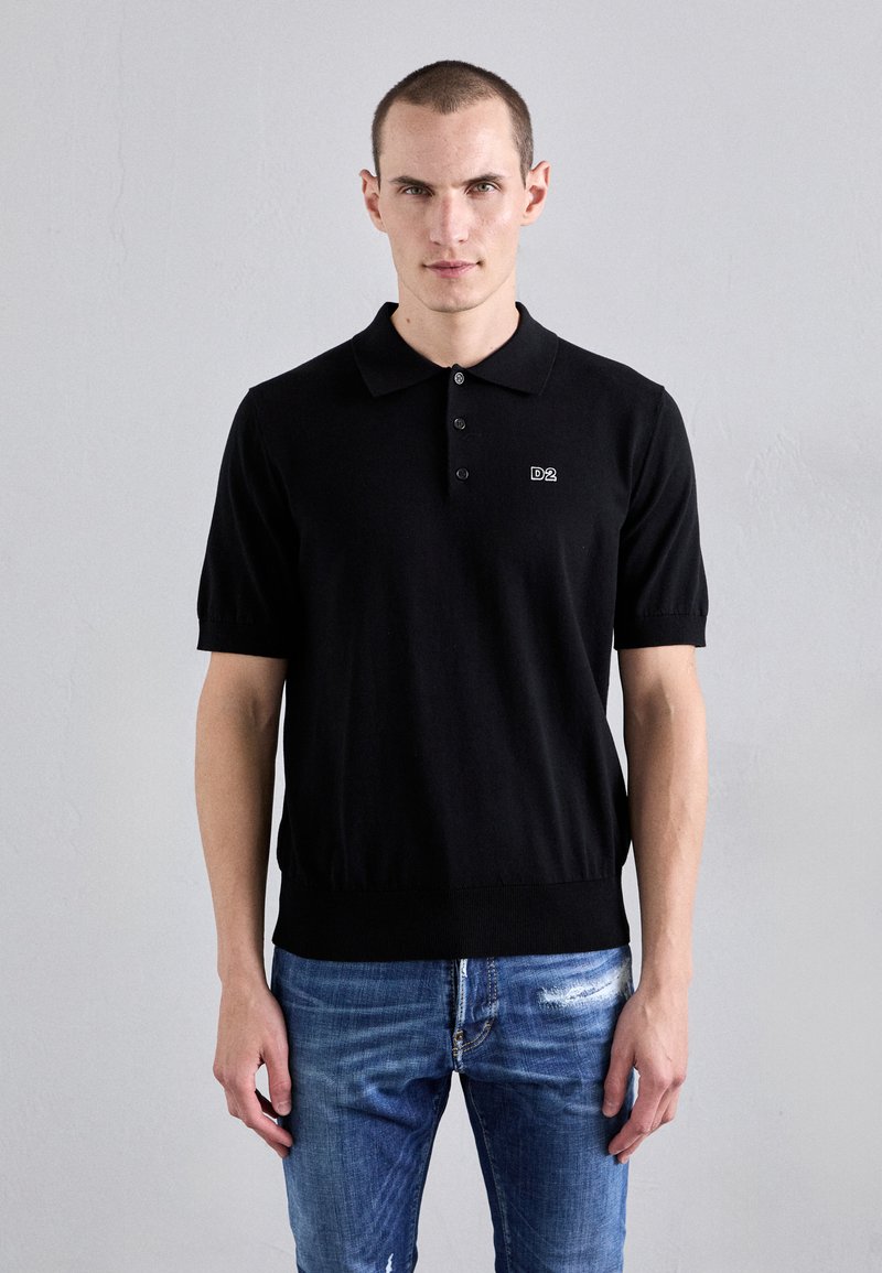 Zwarte polo met korte mouwen, een geribbelde zoom en een drieknoopsluiting, met een geborduurd 'D2' logo op de borst.