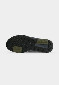 Semelle de chaussure en caoutchouc noire et vert olive avec des crampons profonds et un motif d'adhérence, conçue pour les chaussures de plein air ou de randonnée.