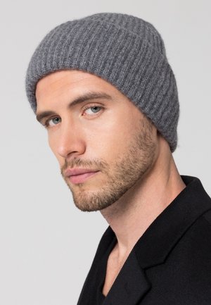 Gray ribbed knit beanie made of soft wool, featuring a snug fit and textured design. Worn on a male model against a neutral background.