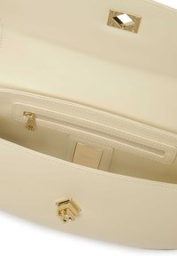 Interiér béžovej koženej kabelky so zlatým zipsovým vreckom, obdĺžnikovou značkovou visačkou a kovovým uzáverom v tvare diamantu. Hladká textúra.