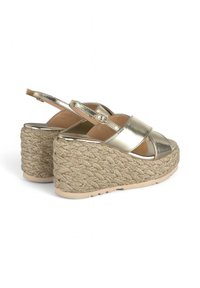 Goldfarbene, metallisch glänzende Keilsandalen mit einer strukturierten Plattform aus natürlichem Material, doppelten Riemen über dem Fuß und einem verstellbaren Knöchelriemen.