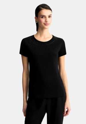 T-shirt nero a maniche corte con un design circolare di piccoli adornamenti attorno al collo, realizzato in tessuto morbido.