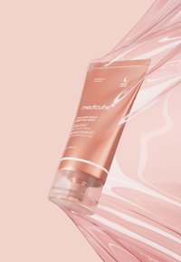 Różowo-złota tubka MediCube Collagen Night Wrapping Mask z przezroczystą podstawą. Gładka powierzchnia, minimalistyczny design, z białym tekstem i akcentami.