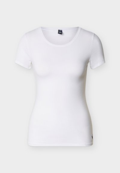 Λευκή γυναικεία κοντομάνικη εφαρμοστή μπλούζα με στρογγυλή λαιμόκοψη και μικρό μαύρο λογότυπο κοντά στο κάτω μέρος, σε απλό φόντο.