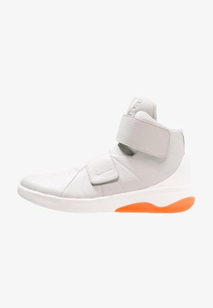 Baskets montantes en cuir blanc avec double bride velcro et accent orange sur la semelle, vue de profil.