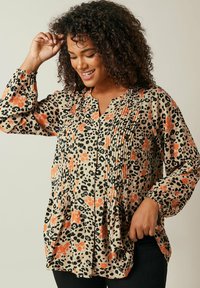 Knapp-up skjorte med beige stof og sort og orange leopardmønster, plisserede detaljer og elastiske manchetter på lange ærmer.