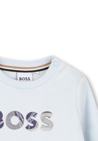 Felpa azzurra con colletto girocollo, caratterizzata da ricami multicolore con la scritta "BOSS", cuciture dettagliate e chiusura a scatto sulla spalla.