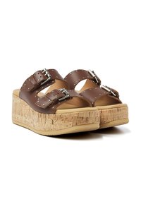 Sandales à plateforme marron avec des semelles en liège, dotées de deux sangles ajustables et d'accents métalliques. Surface texturée avec des découpes arrondies.