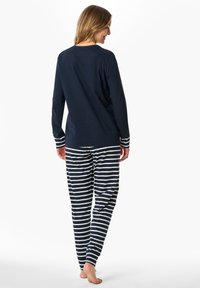 Marinblus med långa ärmar och randiga manschetter, tillsammans med randiga pyjamasbyxor. Mjuk tygkvalitet, avslappnad passform och ankel-lång stil.