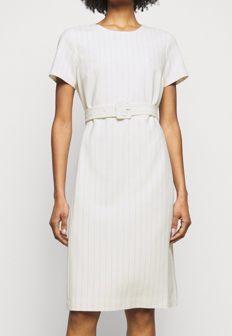 Robe blanche longueur genou, à manches courtes, avec des fines rayures verticales et une ceinture assortie en tissu avec une boucle carrée. Texture lisse.