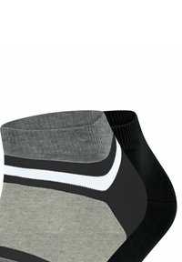 Schwarze und graue Knöchelsocken mit gerippter Textur. Die graue Socke hat einen weißen Streifen; die schwarze Socke hat eine glatte Oberfläche. Beide haben ein niedriges Schnittdesign.