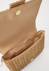Borsa da pochette intrecciata in paglia beige con una foderatura in tessuto liscio, dotata di una chiusura a scatto dorata e di una piccola tasca interna.