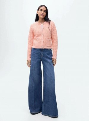 Rosa strukturierten Cardigan mit Rundhalsausschnitt und Knöpfen, kombiniert mit weiten blauen Jeans. Einfaches Design mit einer lässigen Passform.