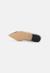 Scarpa con tacco alto in suede grigio con punta affusolata, dotata di una suola in suede crema e di un cappuccio del tacco in gomma nera. Dettaglio su misura sulla suola.