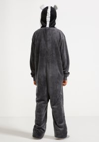 Combinaison en peluche grise avec une capuche, ornée d'accents noirs et blancs, d'oreilles arrondies et d'une texture douce. Coupe ample avec des manches longues et un pantalon.