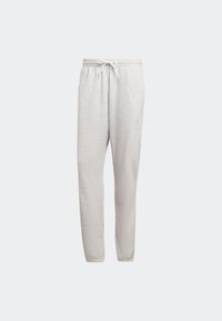 Ljusgrå sweatpants med elastisk midja, vit dragsko, avsmalnande ben och elastiska muddar mot en plain ljus bakgrund.