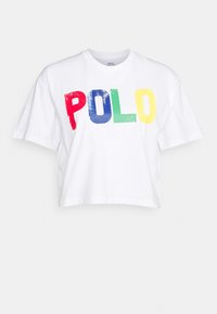 Vit bomullskar t-shirt med korta ärmar som har djärv, flerfärgad "POLO"-text i röd, blå, grön och gul med en något sliten yta.