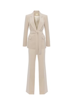 Beżowy, dopasowany garnitur z długą marynarką z szerokimi klapami, paskiem wiązanym w talii, kieszeniami z patkami oraz pasujące spodnie o prostych nogawkach.