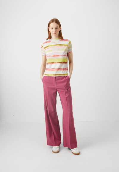 Stripet strikket topp i hvit, gul, rosa og grønn, kombinert med brede rosa bukser og hvite sneakers.