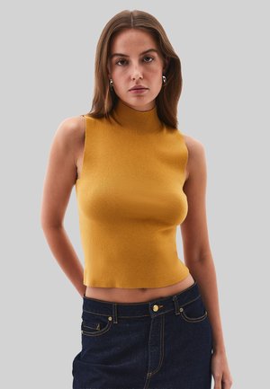 Mosterdgele, geribbelde mouwloze top met hoge hals en een aansluitend ontwerp, gecombineerd met een donkerdenim rok met voorste knopen en zakken.