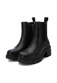 Botas de cuero negro hasta el tobillo con tacones de bloque gruesos, paneles laterales elásticos y un detalle de cremallera en un lado. Textura suave con acentos mínimos.