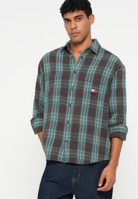 Brun og tealternet flannel skjorte med lange ærmer, knappelukning foran og en brystlomme. Blød tekstur, afslappet design og synlige sømdetaljer.