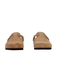 Sabots en suède beige avec une semelle en caoutchouc plate, comportant deux sangles réglables sur le dessus et un design lisse, sans embellissement.