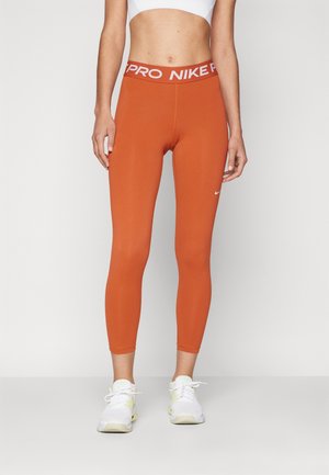 Orange atletiske leggings med en hvid "PRO NIKE" talje. Lavet af strækbart stof, med en tætsiddende pasform og minimal branding.