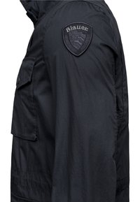 Czarna kurtka z teksturowanej tkaniny, z bocznymi kieszeniami oraz widoczną naszywką z logo Blauer na ramieniu.