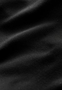 Tessuto nero con una superficie liscia, caratterizzato da morbide e sottili pieghe e una superficie uniforme senza motivi o accessori visibili.