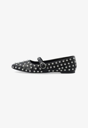 Chaussure plate noire avec un bout rond, ornée de clous en argent, et une sangle à la cheville avec une boucle en métal. Texture lisse, talon bas.