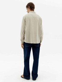 Hellbeige Langarmhemd, lockere Passform, strukturiert; kombiniert mit dunklen Jeans, gerade geschnitten, minimale Details, bequeme Schuhe.