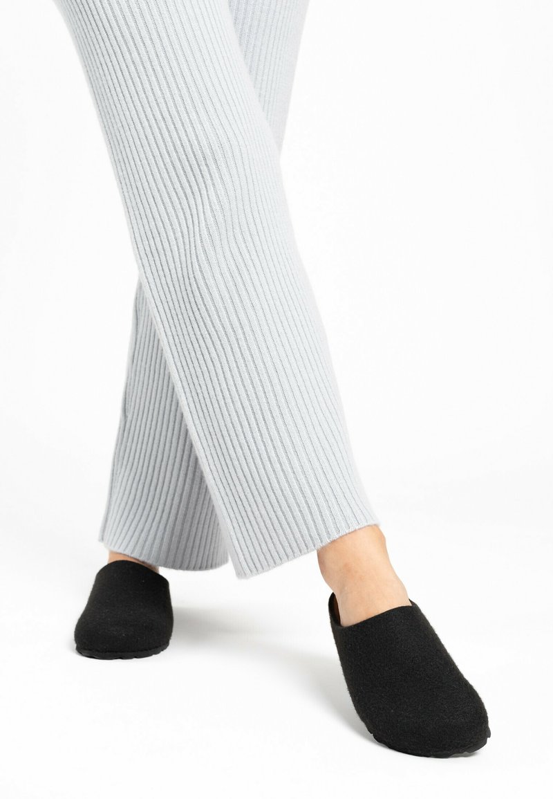 Czarne filcowe kapcie o gładkiej powierzchni, z okrągłym noskiem i wsuwanym fasonem, zestawione z jasnoszarymi ribbed spodniami.
