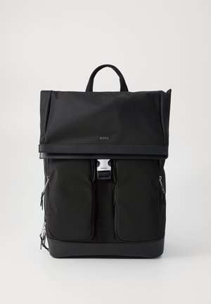 Zaino nero con esterno in nylon, spallacci regolabili, tasche frontali con zip e maniglia superiore. Logo visibile nella parte anteriore.