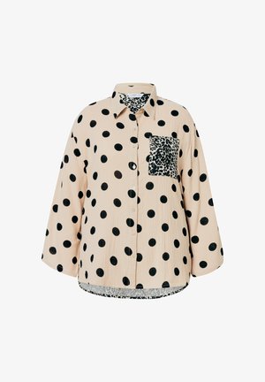 Camisa beige con grandes lunares negros, diseño de botones y un bolsillo de estampado de leopardo. Presenta mangas sueltas y tejido texturizado.