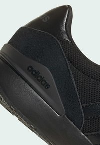 Czarne buty sportowe z cholewką wykonaną z mieszanych materiałów, zamszu i tkaniny, z teksturowaną podeszwą oraz wytłoczonym logo.