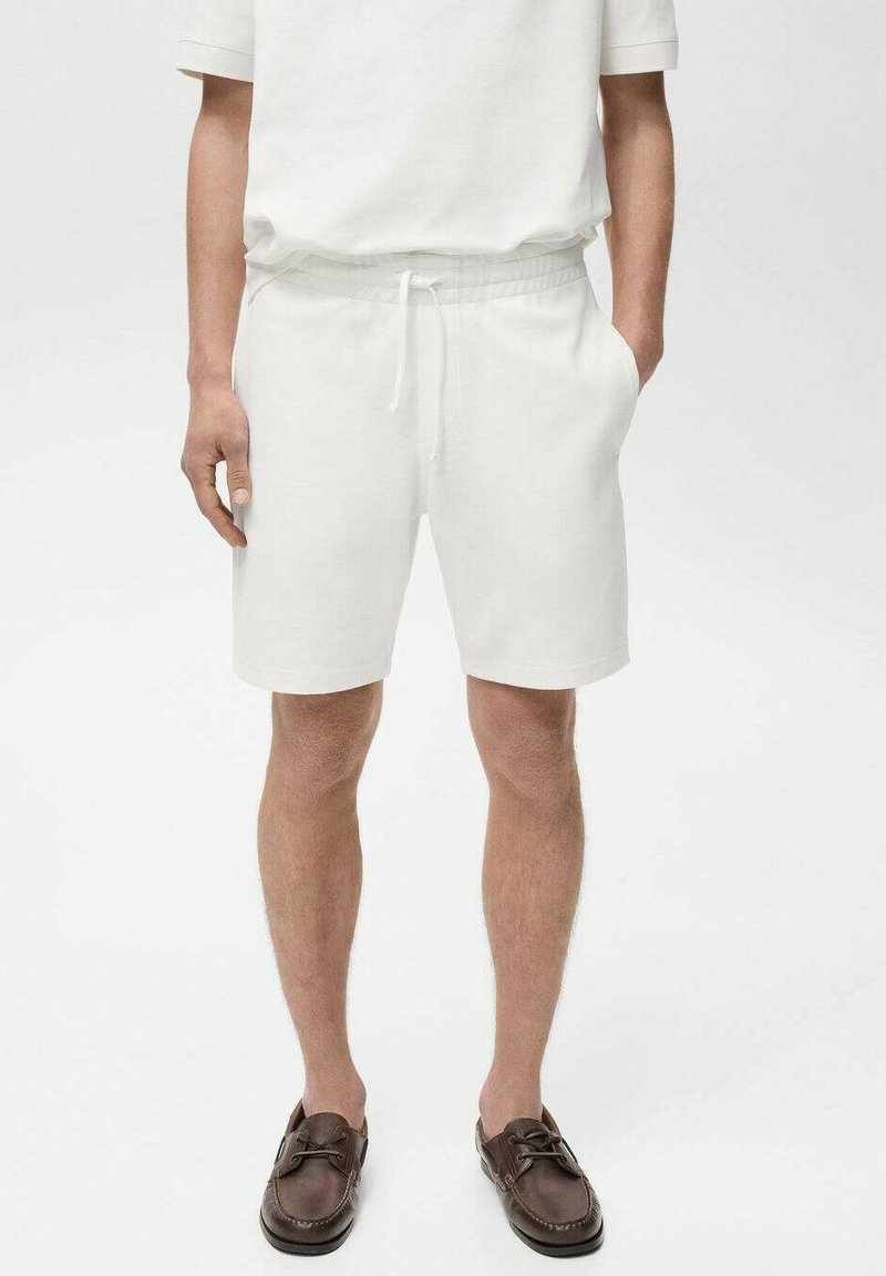 Shorts en coton blanc avec une taille élastique et un cordon de serrage, dotés de poches sur les côtés et d'une coupe décontractée. Texture lisse, design simple.