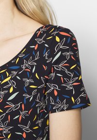 Short-sleeve top featuring a dark background with colorful leaf patterns in red, yellow, blue, and green on a smooth, soft fabric.