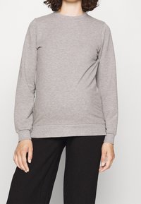 Sudadera gris de manga larga con cuello redondo, puños y bajo ribeteados. Tejido suave con una textura lisa, combinado con pantalones de pierna ancha negros.