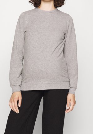 Grå långärmad sweatshirt med rund halsringning, ribbade muddar och nederkant. Mjuk tyg med en slät textur, tillsammans med svarta vida byxor.
