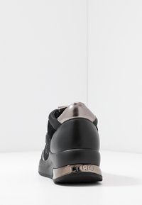 Sneaker nera con materiali in rete e pelle, dettaglio in metallo argento sul tallone e logo sul retro. Forma arrotondata con suola imbottita.