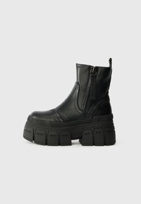 Botas de tornozelo pretas feitas de couro liso, com sola plataforma grossa, fecho éclair frontal e detalhes de costura texturizada.